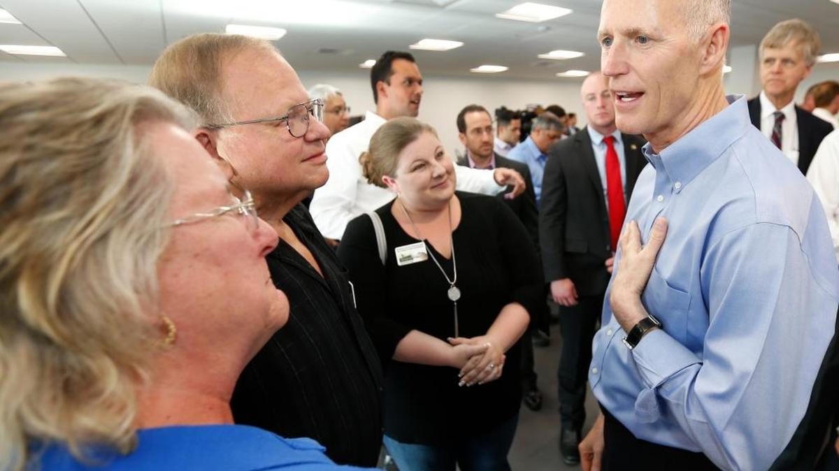 Florida Gov. Rick Scott, right, speaks to attendees after a news conference Wednesday in Sunrise.