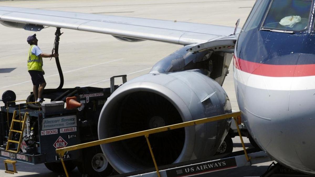 A worker hooks up a fuel hose to an airplane at Tampa International Airport in Tampa.