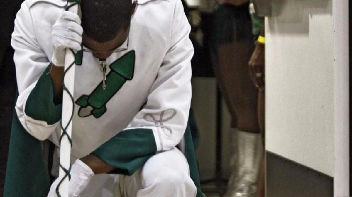 Drum Major Andre Young kneels in prayer in the doorway prior to performing with Miami Central High School band in May 2009.