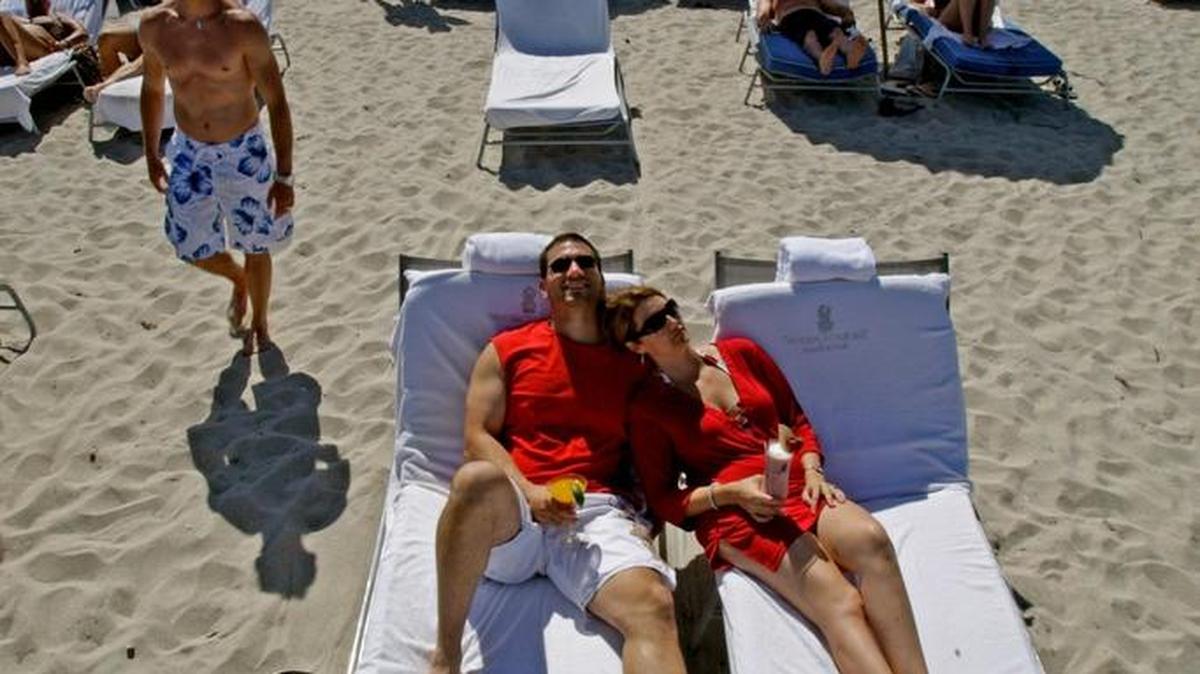 Chris and Jen Scala of Philadelphia sit on the beach behind the Ritz Carlton on Miami Beach, Monday August 3, 2016.