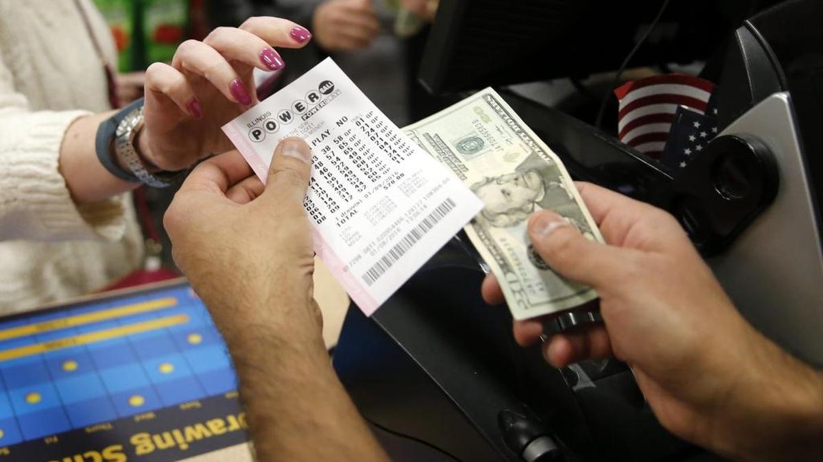 File: Biren Shah, right, sells a Powerball lottery ticket to a patron at his news stand as the multi-state jackpot reaches $800 million, Friday, Jan. 8, 2016, in Chicago. With ticket sales doubling previous records, the odds are growing that someone will win Saturdays record jackpot, but if no one wins the top prize, next weeks drawing is expected to soar past $1 billion. (AP Photo/Charles Rex Arbogast)
