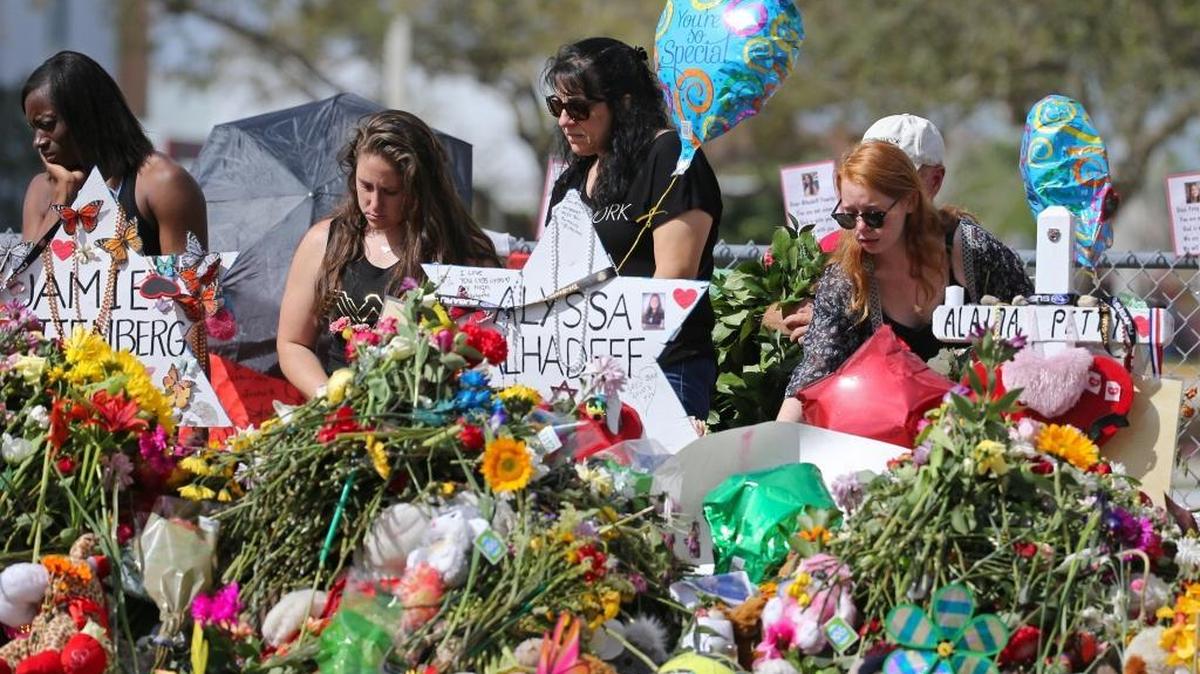 Mourners bring flowers as they pay tribute at a memorial for the victims of the shooting at Marjory Stoneman Douglas High School on Sunday, February 25, 2018.