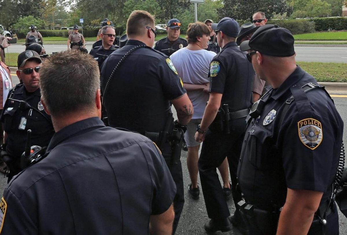 An alt-right demonstrator who held a sign that read “Founding fathers=alt-right'’ was detained by police after he was said to have brandished a weapon during Thursday's protest on the campus of the University of Florida. White nationalist Richard Spencer spoke at the campus, drawing more protesters than supporters.