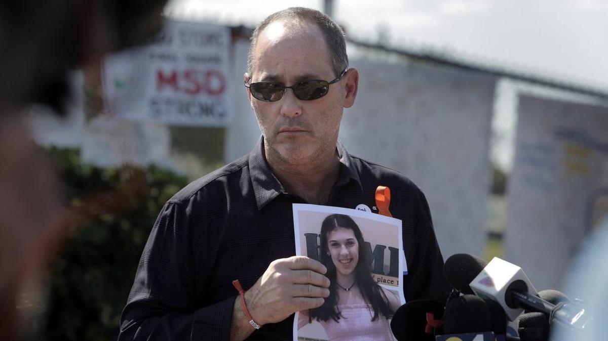 In this Miami Herald file photo, Fred Guttenberg, father of Jaime Guttenberg, who was killed in the Parkland massacre, holds a photo of Jaime as he listens to questions from reporters in front of Marjory Stoneman Douglas High School.