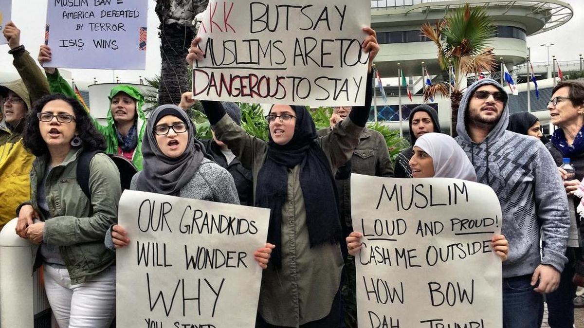 Protesters hold up signs against President Donald Trump’s refugee ban at Miami International Airport on Sunday.