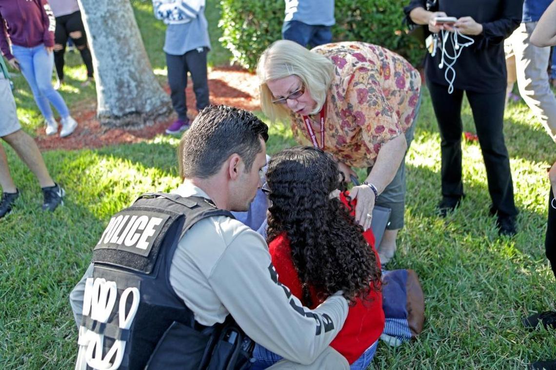 A traumatized Marjory Stoneman Douglas student is assisted by a law enforcement officer. She and hundreds of classmates were able to flee the high school where Nikolas Cruz opened fire with an AR-15 semi-automatic, killing 17, on Feb. 14, 2018.