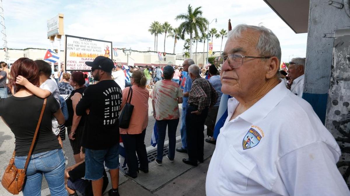 Rafael Torre, right, 80, watches as members of the Cuban community react to the death of Fidel Castro, Saturday, Nov. 26, 2016, in the Little Havana area in Miami. Torre participated in the failed CIA-backed Bay of Pigs invasion in 1961 and wore a "Bay of Pigs Veteran" shirt to Saturday's demonstration.