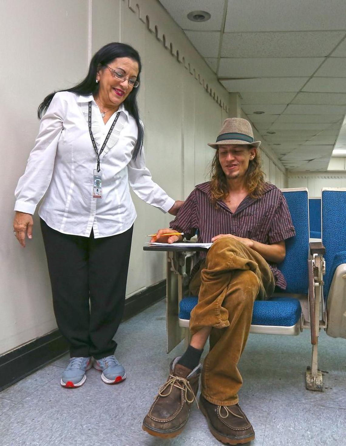 Rebecca Asad Alvarez, an employee at the Department of Labor in San Juan, helps Julio Vallejo Gonzalez apply for unemployment benefits.