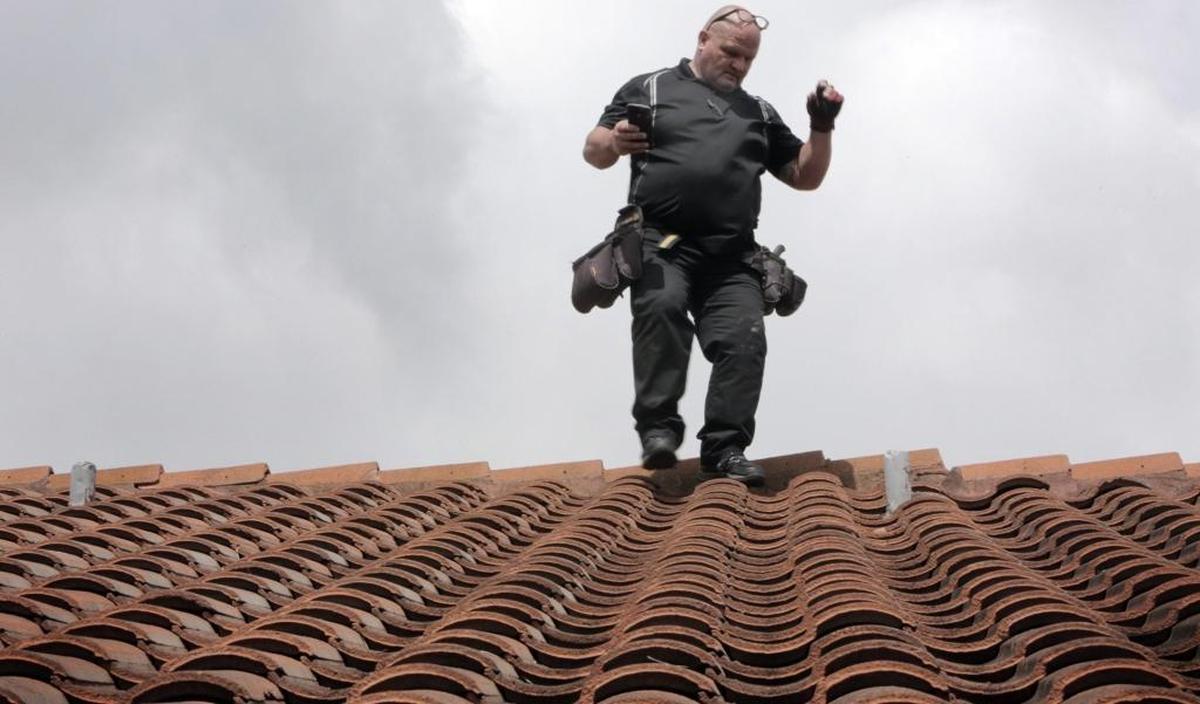 Catastrophic claims specialist Eric Kline inspects the roof of a house in Kendall.