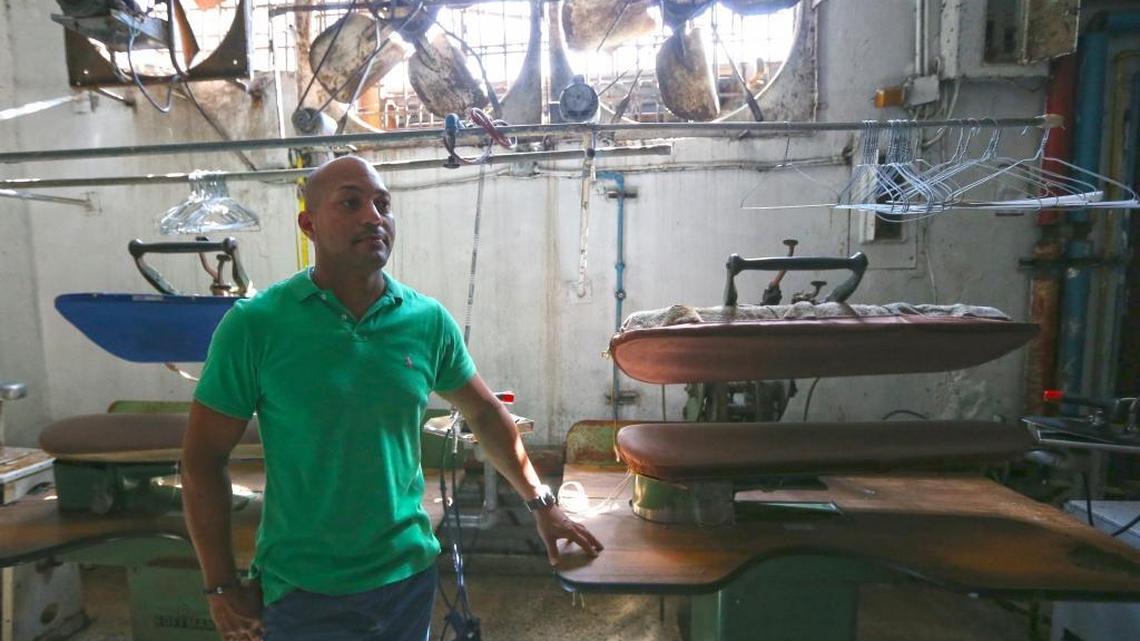 Richard Davila, the owner of Martinizing Dry Cleaning in Humacao, next to the ironing press machine at his still-shuttered shop. He can’t afford a $40,000 generator he needs to power his business and he’s stuck with $20,000 in unpaid work.