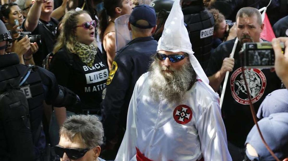Members of the KKK are escorted by police past protesters during a rally in Charlottesville, Virginia.