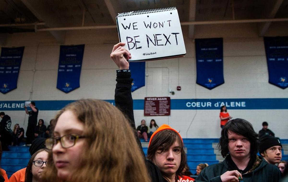 Coeur d'Alene High School 10th grader John Marfice holds his sign during the walkout assembly at the school in Coeur d'Alene, Idaho, on Wednesday.