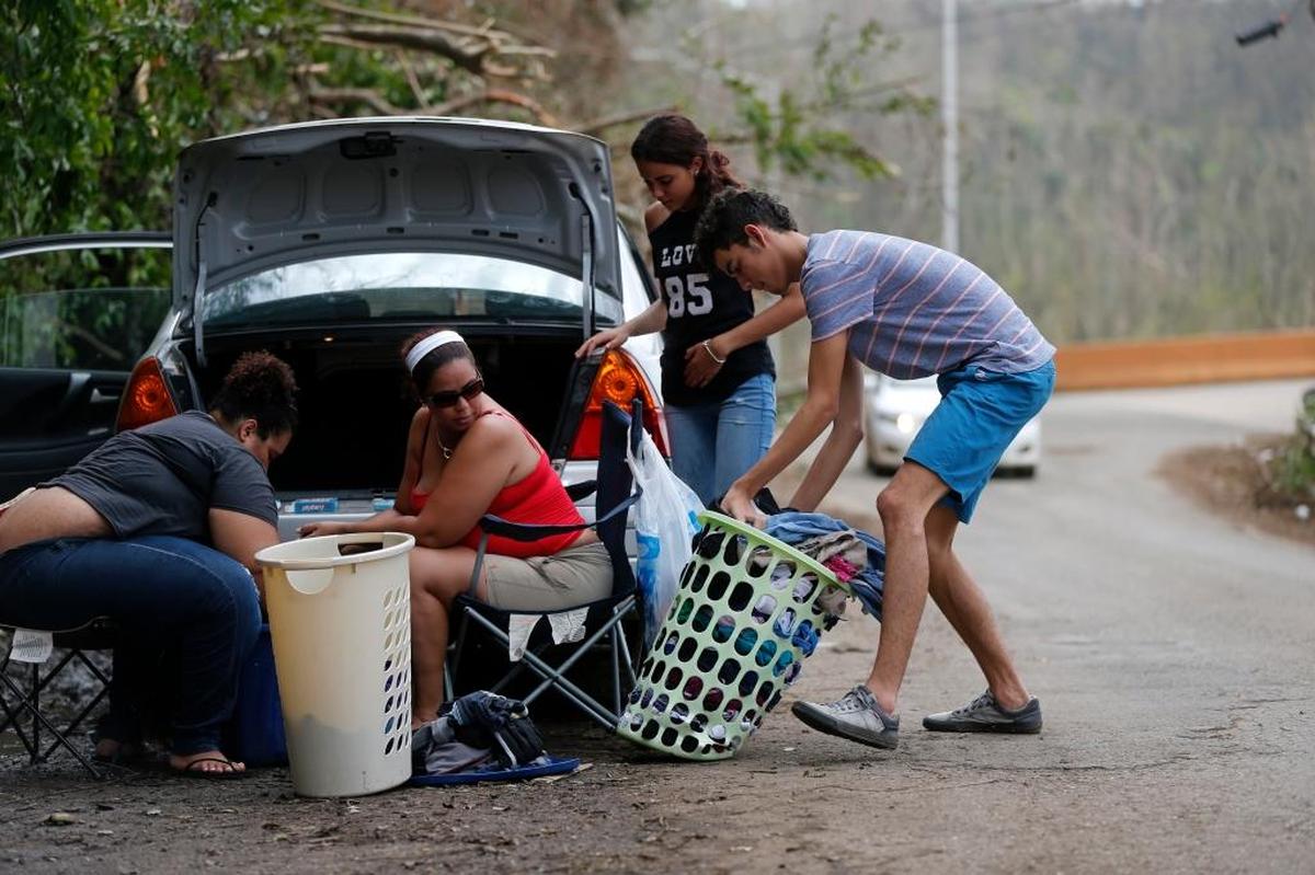 A family washes clothes on the side of the road, utilizing water running off the mountain in Montebello, Puerto Rico, in the aftermath of Hurricane Maria, Tuesday.