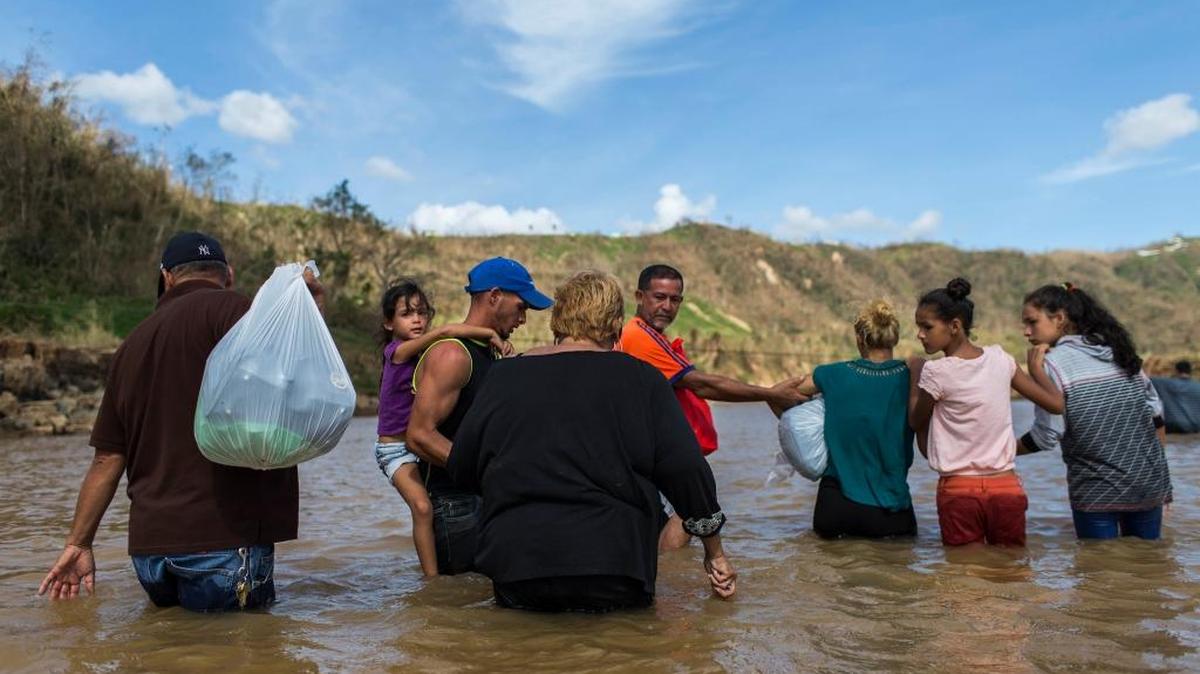 A family crosses a river in Morovis, Puerto Rico. Residents of the San Lorenzo neighborhood can't access their houses because Hurricane Maria destroyed the bridge that connects them with the main access road.