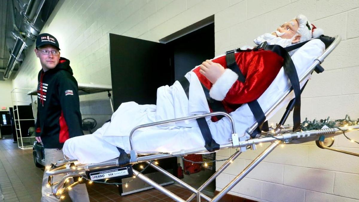 Volunteer firefighter Ryan Lonas of the Shawnee Volunteer Fire and Rescue Company in Winchester, Va. is shown Friday, Dec. 22, 2017 with one of the Christmas decorations inside the firehall that features Santa on a stretcher with Christmas lights.