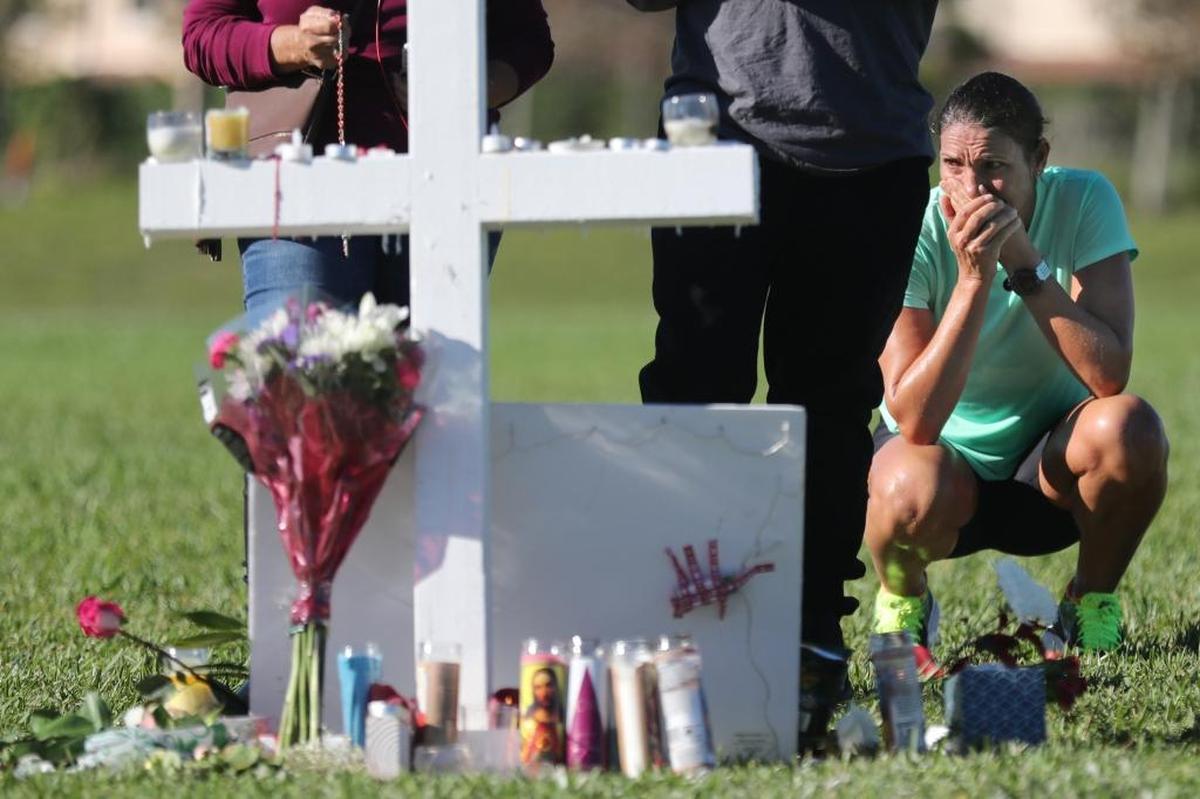 Maria Creed is overcome with emotion Friday as she crouches in front of one of the memorial crosses at Pine Trails Park in Parkland. Her son, Michael Creed, is a sophomore at Marjory Stoneman Douglas High School