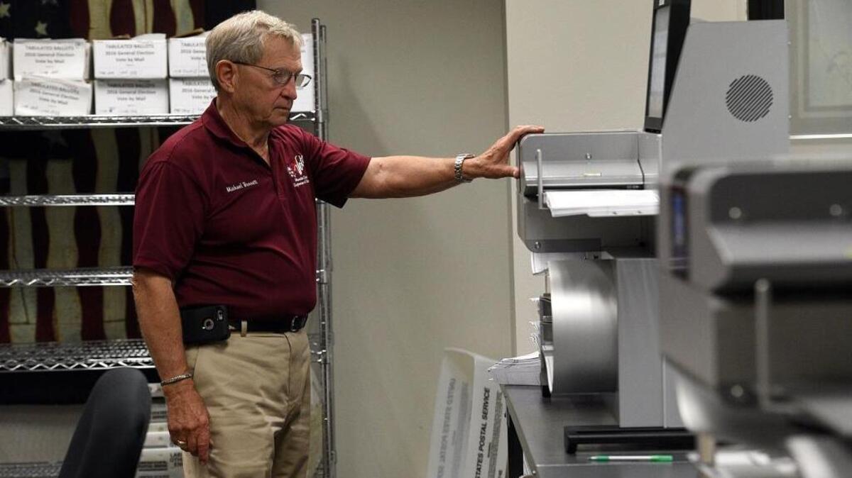 Supervisor of Elections Michael Bennett tabulates ballots in a high-speed voting tabulator Tuesday.
