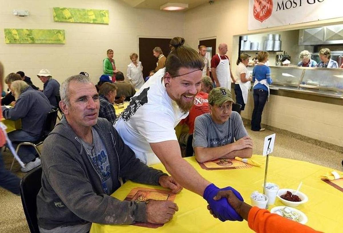 Volunteer Sean Roberts shakes hands Thanksgiving Day 2017 with a diner at the Salvation Army’s Thanksgiving meal.