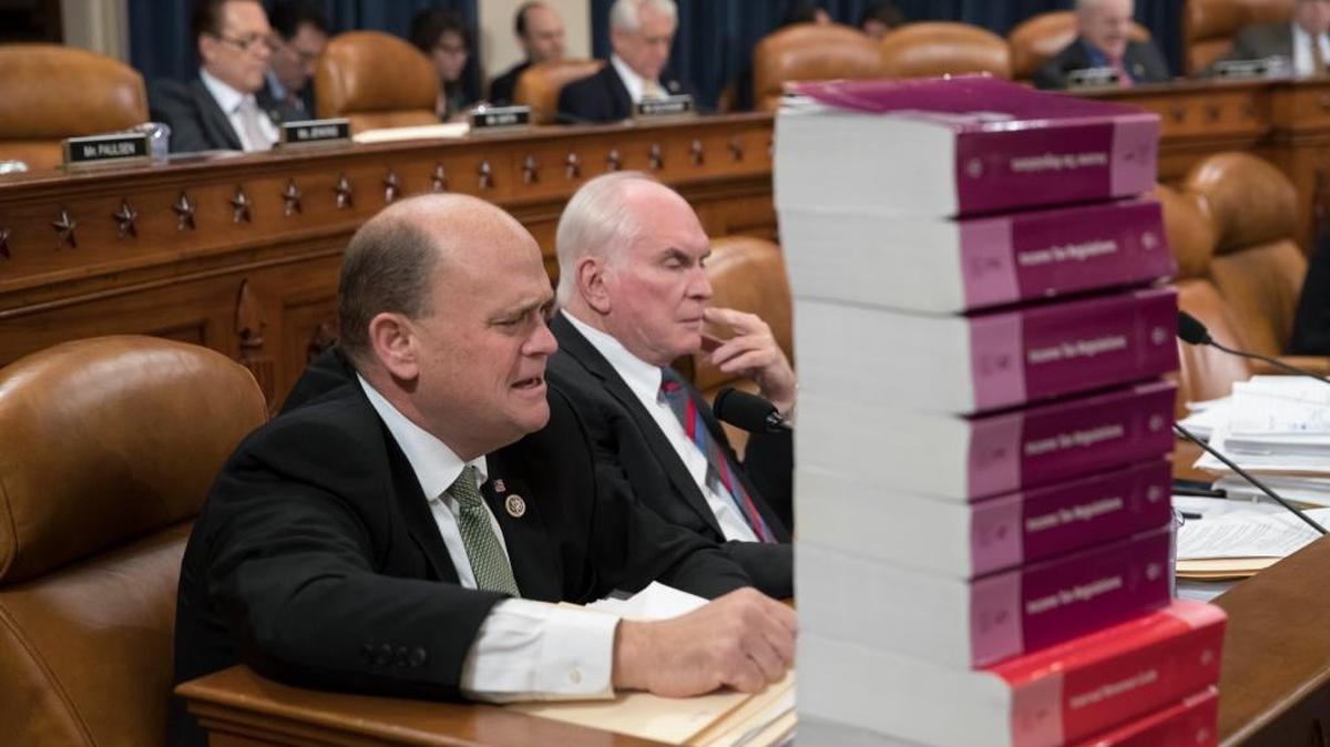 Seated behind a stack of IRS and tax volumes, Rep. Tom Reed, R-N.Y., left, joined by Rep. Mike Kelly, R-Pa., appeals Wednesday to his Democratic opposition during debate on amendments to the House Republican tax reform plan.