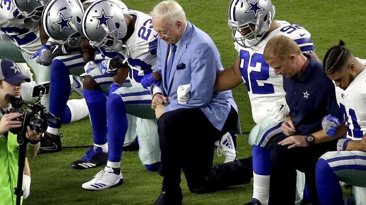 The Dallas Cowboys, led by owner Jerry Jones, center, take a knee prior to the national anthem prior to an NFL football game against the Arizona Cardinals, Sept. 25, in Glendale, Ariz.