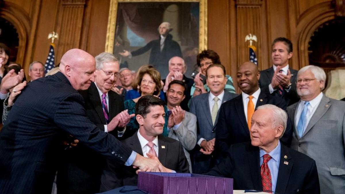 Congressmen celebrate after Speaker of the House Paul Ryan and Senate Finance Committee Chairman Orrin Hatch sign the final version of the GOP tax bill Thursday.