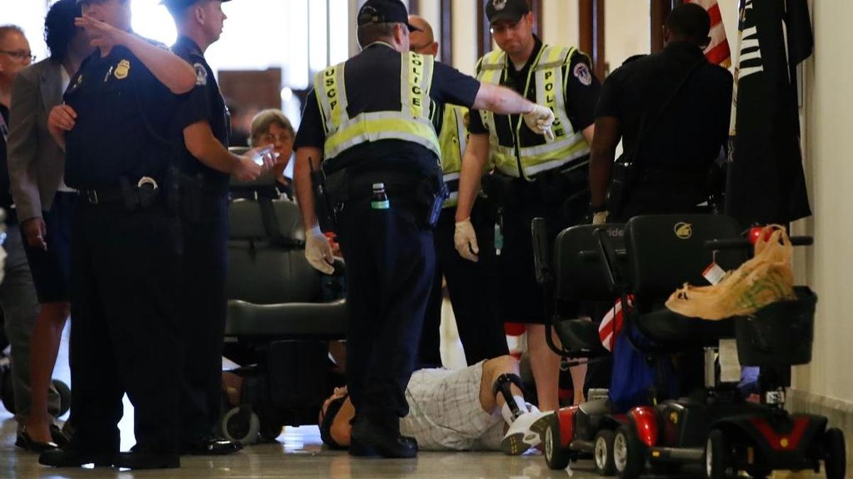 Capitol Police prepare to remove a man from a sit-in of Senate Majority Leader Mitch McConnell's office, as he and others protest proposed caps to Medicaid Thursday, June 22, 2017, on Capitol Hill in Washington.