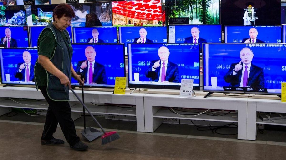 A cleaner walks past TV sets showing Russian President Vladimir Putin during his annual live call-in show in a shop in Moscow, Russia, Thursday, June 15.