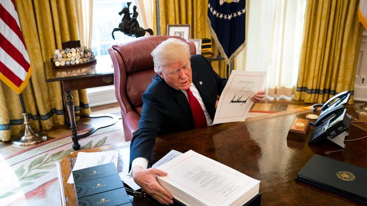 President Donald Trump displays his signature on a sweeping tax bill in the Oval Office of the White House, in Washington, Dec. 22, 2017. Trump signed the bill on Friday that Republicans promise will benefit the middle class, despite warnings from Democrats that the new law could be harmful to the country.