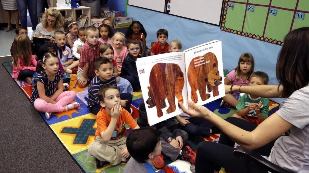 FILE - Kindergarten students listen as a teacher reads on the first day of school in Beaverton, Ore. A last-minute amendment to the Republicans' tax plan would allow parents to use savings from 529 education savings accounts to pay for K-12 education, including homeschool expenses.