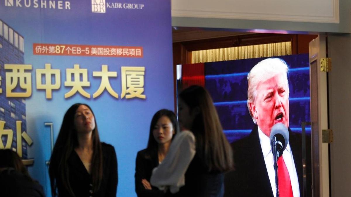 A projector screen shows a footage of U.S. President Donald Trump as workers wait for investors at a reception desk during an event promoting EB-5 investment in a Kushner Companies development at a hotel in Shanghai, China, Sunday, May 7, 2017. The sister of President Trump's son-in-law, Jared Kushner, has been courting Chinese investors using a much-criticized federal visa program that provides a path toward obtaining green cards.