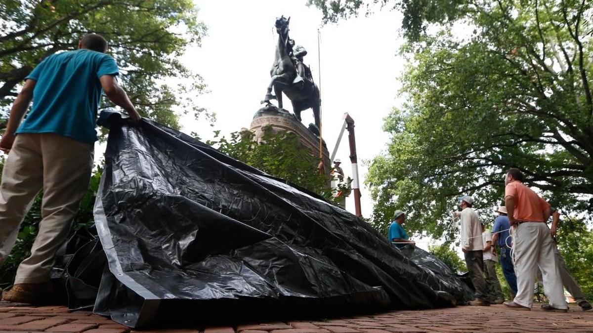 City workers prepare to drape a tarp over the statue of Confederate General Stonewall Jackson in Justice park in Charlottesville, Va., Wednesday, Aug. 23, 2017. The move intended to symbolize the city's mourning for a woman killed while protesting a white nationalist rally earlier this month.