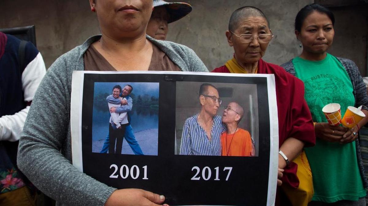 An exile Tibetan carries a placard featuring photos of late Nobel Peace Prize laureate Xiaobo Liu, China's most famous political prisoner, during a candlelit vigil Friday to mourn Liu's death, in Dharmsala, India.