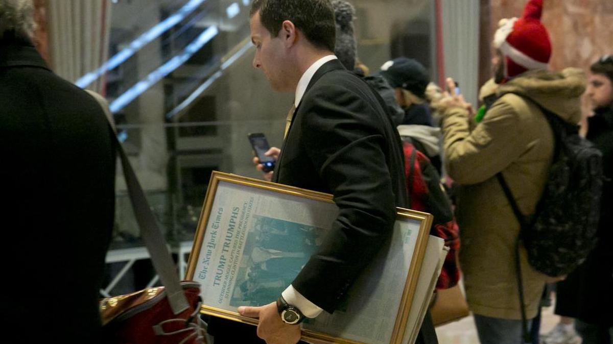 A man carries a framed New York Times front page of President-elect Donald Trump's victory, through the lobby of the Trump Tower in New York, Tuesday, Nov. 22.
