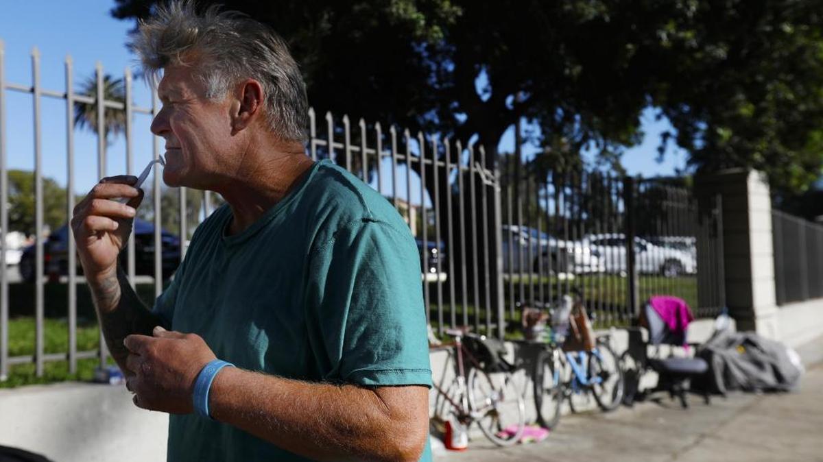 Kevin Eugene Powell, 58, shaves his face outside the VA Medical Center gate, in West Los Angeles, on December 13, 2017. He said he is a veteran and has been homeless for three years.