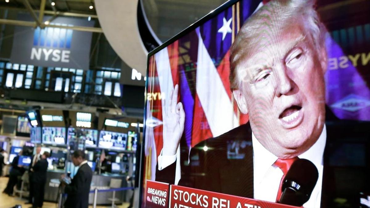 FILE- In this Nov. 9, 2016, file photo an image of President-elect Donald Trump appears on a television screen on the floor of the New York Stock Exchange.