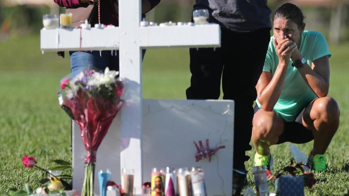 Maria Creed is overcome with emotion as she crouches in front of one of the memorial crosses at Pine Trails Park in Parkland, Fla., on Friday. Her son, Michael Creed, is a sophomore at Marjory Stoneman Douglas High School