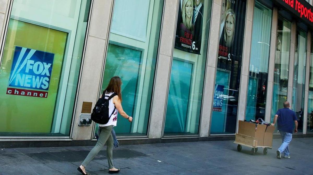 FILE- In this Aug. 1, 2017, file photo, people pass the News Corporation headquarters building and Fox News studios in New York.