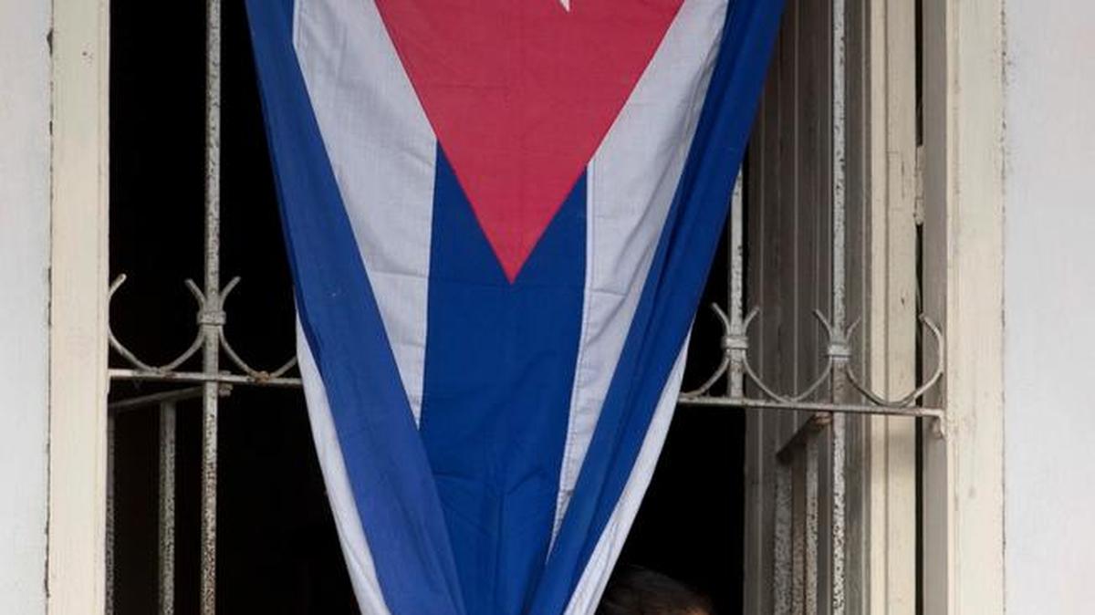 A woman waits behind a Cuban flag for the arrival of Fidel Castro’s funeral procession in Esperanza, Cuba, on Wednesday.