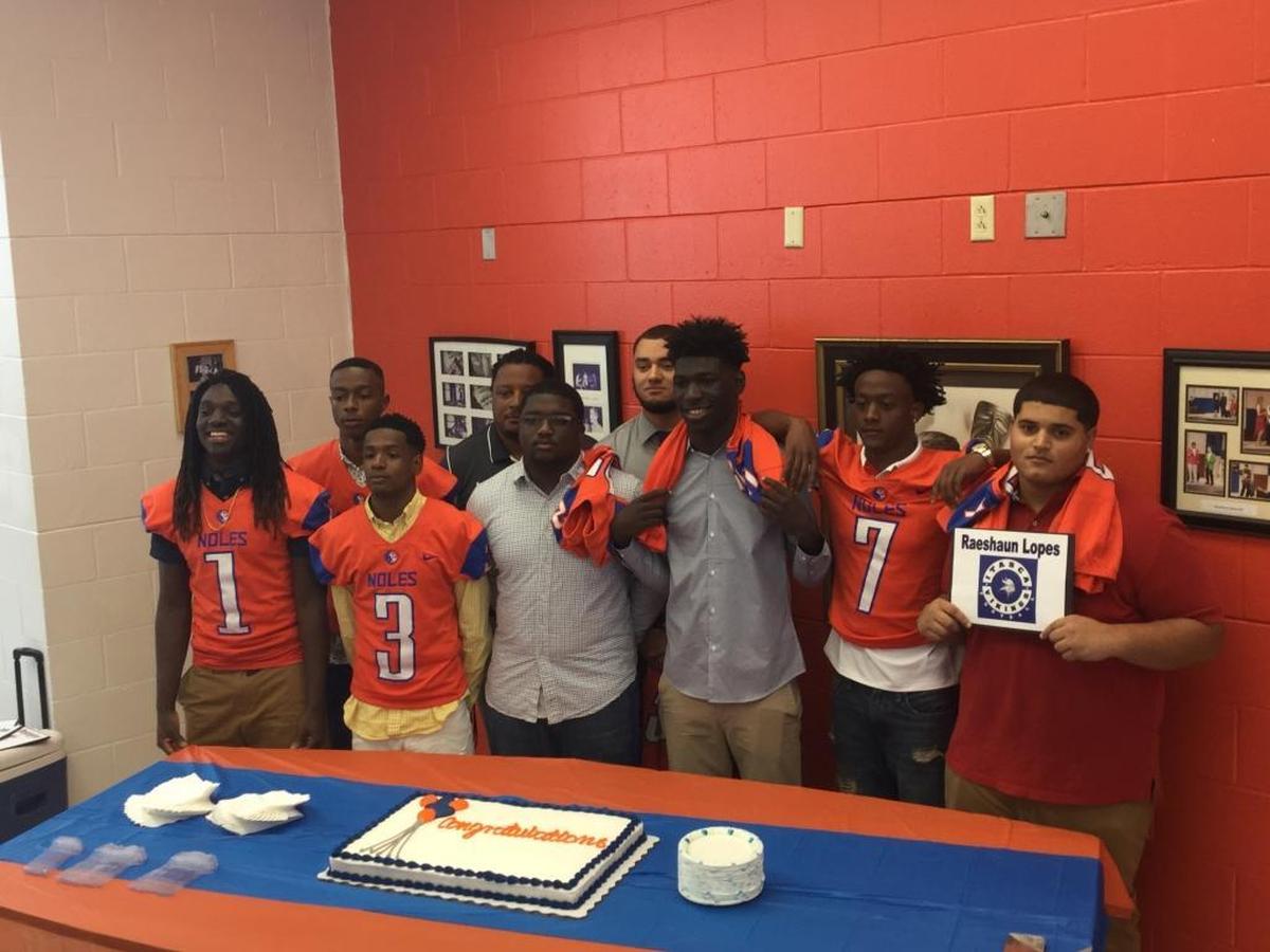 Southeast High football players J.T. Galloway (far left), Damon Poole (back left), Tyler Stevenson (second from left in front), Teriq Houston (front left center), Devin Logan (back row right), Damien Washington (front center), Korey Waters (right center) and Raeshaun Lopes (far right) surround former head coach Rashad West (back row center) on National Signing Day.