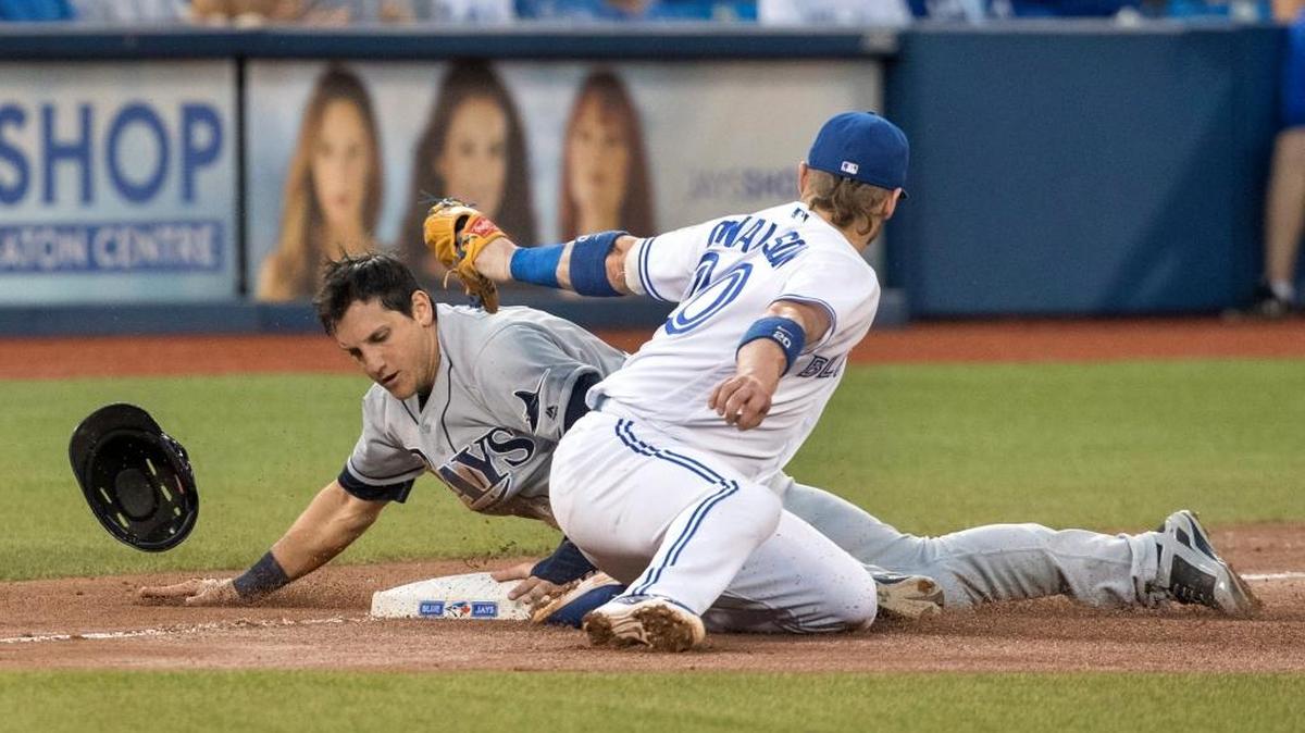The Tampa Bay Rays’ Mikie Mahtook, left, slides safely under the tag attempt at third base by the Toronto Blue Jays’ Josh Donaldson during the fourth inning in Toronto on Monday.
