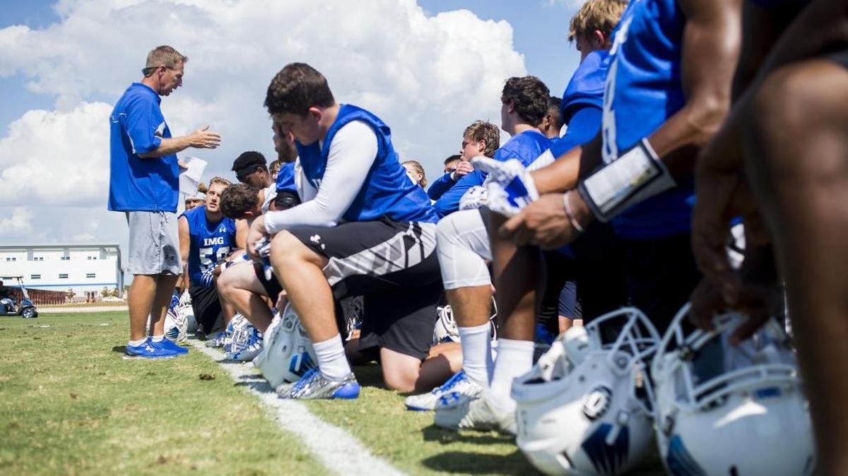 Head football coach Kevin Wright talks to players after IMG Academy's football practice during the spring. Approximately 120 players are expected to put on the Ascenders’ football uniform this season as part of two varsity-level teams.