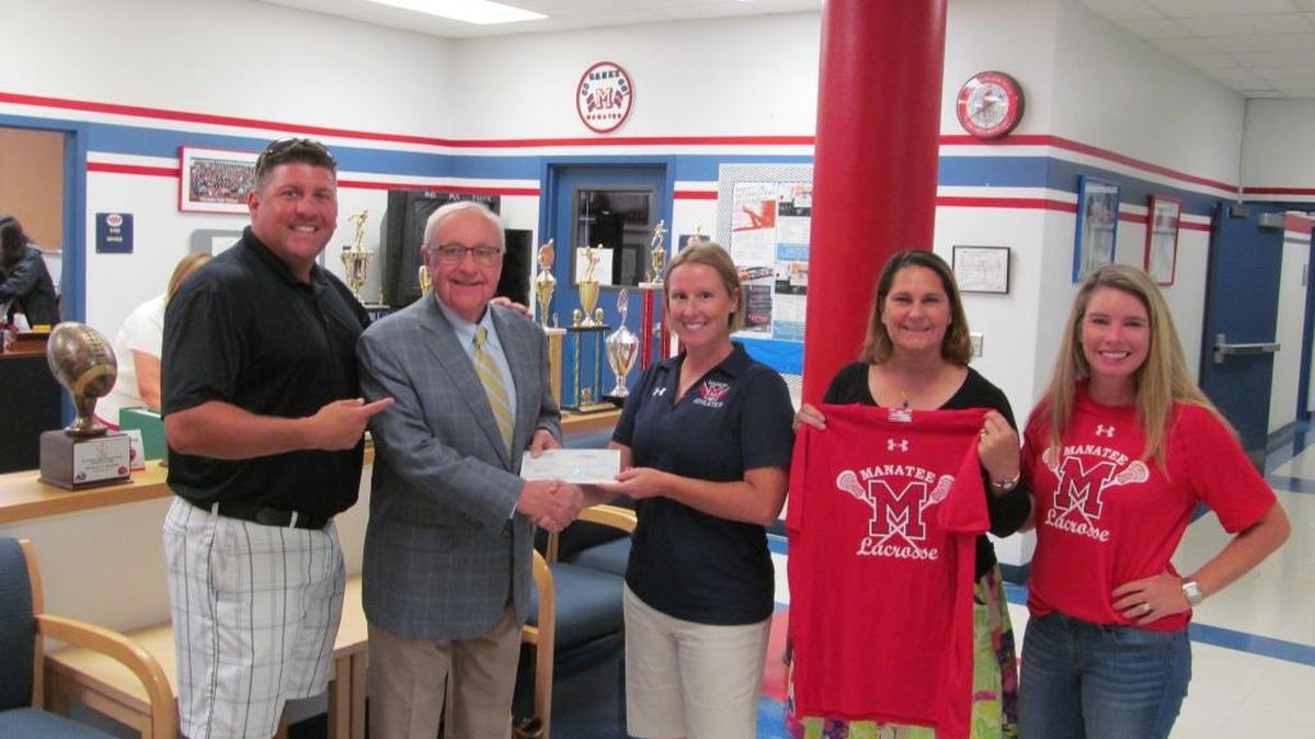Matt Faul, president of the Manatee High School lacrosse booster club; David Eckel, owner of Wagner Realty; Danielle LaPoint, Manatee athletic director; Natalie Russell, operations manager for Wagner Realty; and Tracey Rosa, vice-president of the lacrosse booster club, pose on Tuesday while presenting a check for $5,000 toward the fund whose goal is the creation of boys and girls lacrosse programs at the school.