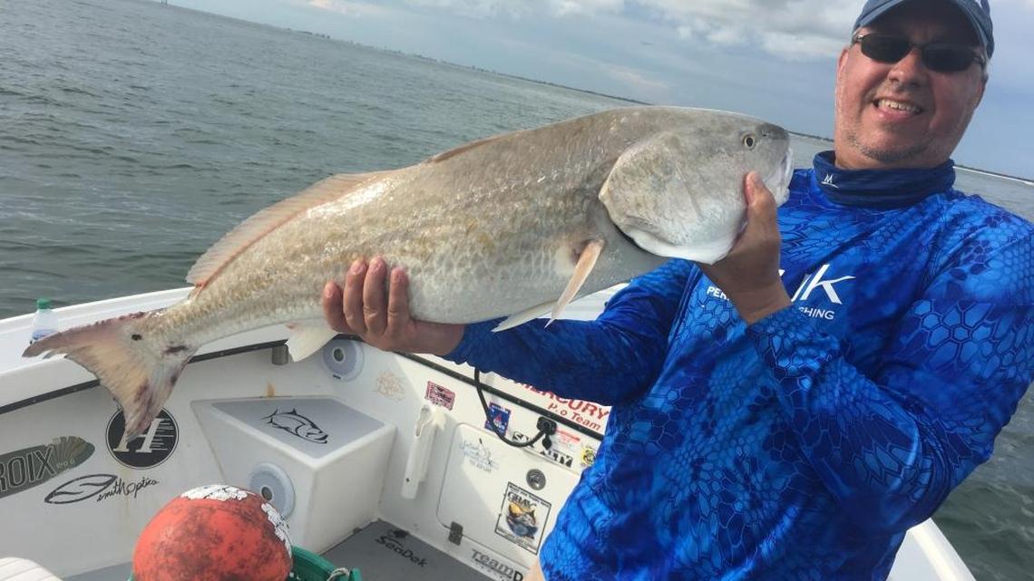 Russell Johnson, from Texas, holds the large redfish he caught while fishing with Capt. Jason Stock on Friday evening. It is getting harder to find redfish in the region.