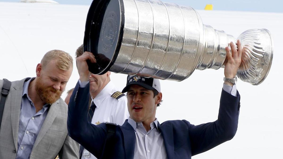 The Pittsburgh Penguins’ Sidney Crosby, right, gets off the jet from California with the Stanley Cup beside Patric Hornqvist after the team’s flight on Monday.