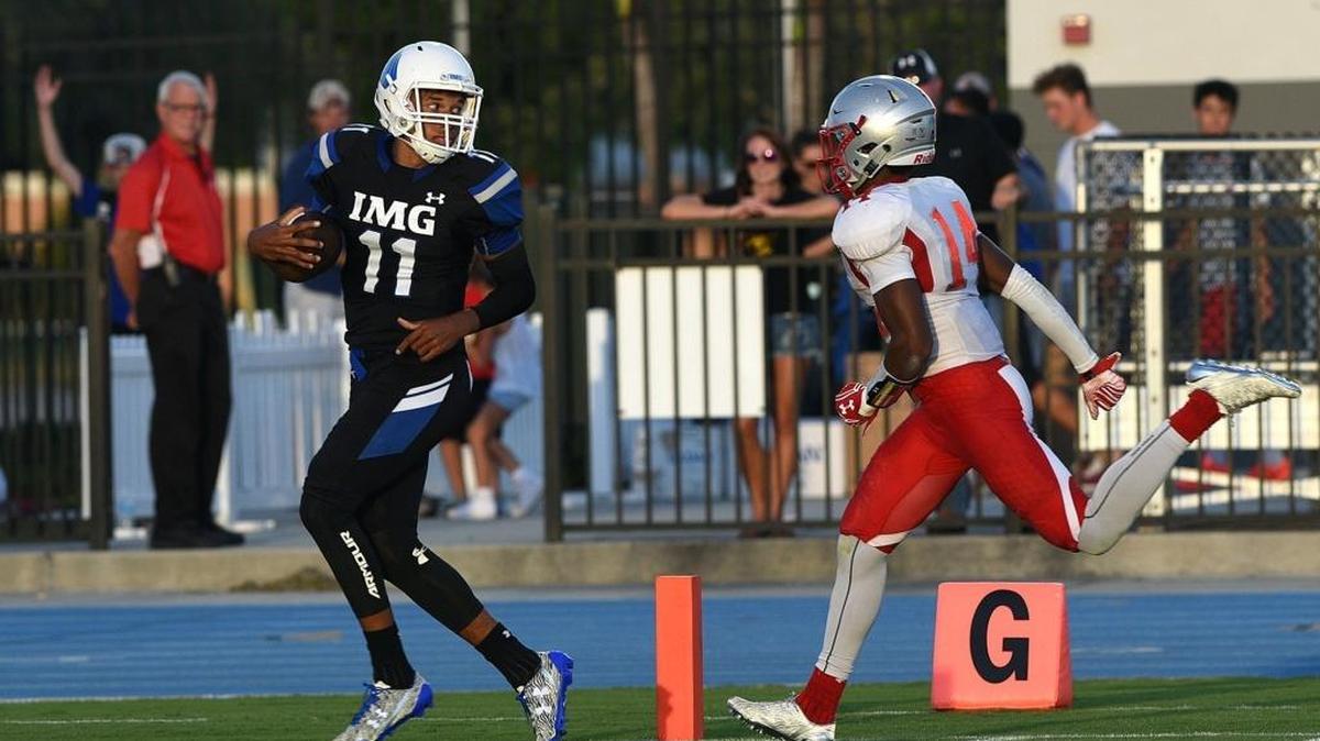 IMG's Kellen Mond looks over his shoulder as he crosses the goal line to St. Johns' Jamal Gay at IMG's home game on Saturday, Sept. 17 in Bradenton. HERALD FILE PHOTO