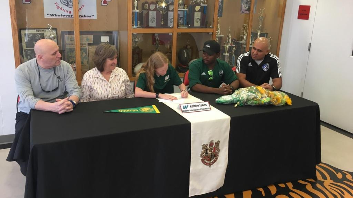 Palmetto High School soccer player Kaitlyn Jones signs a letter of intent to play at Webber International University on Thursday. She is flanked by (from left) parents BJ Jones and Karen Jones, Webber International University assistant coach Derrick Smith and ECNL Director for the West Florida Flames club soccer team Jorge Zavala.