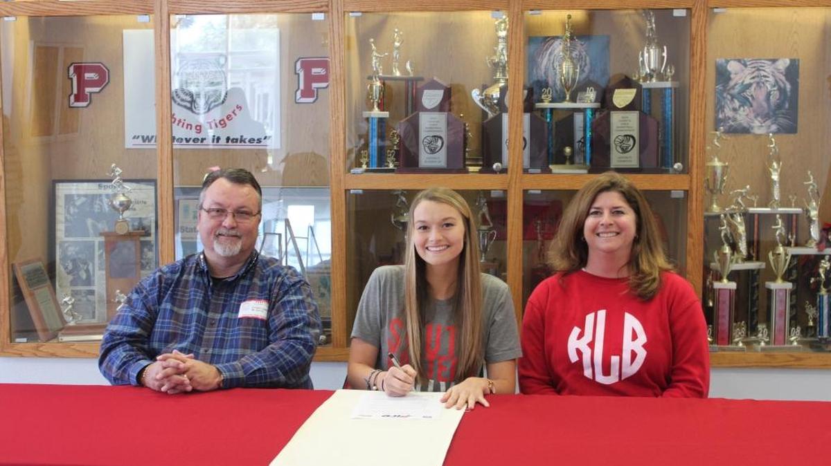Sarah Liggins (center) signs her National Letter of Intent to Southeastern University soccer with her father, Ernie Liggins, and mother, Kristi Liggins, at her side.