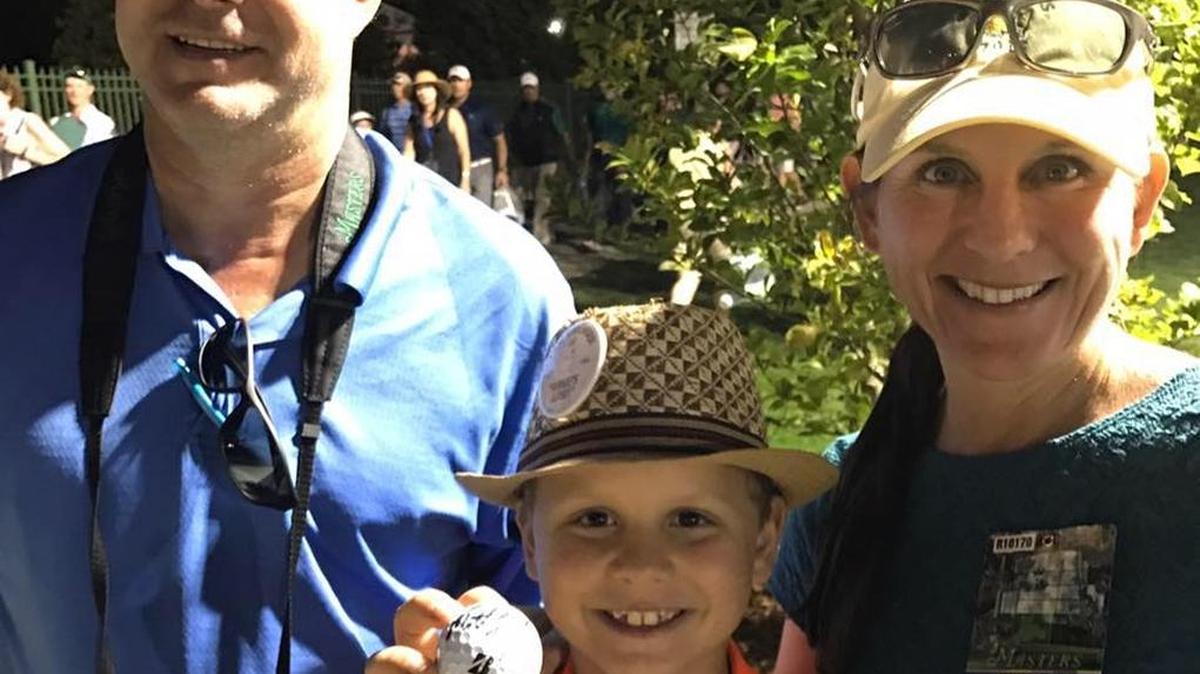Owen Lockaby, with his parents Jay, left, and Tracy, show the ball that Matt Kuchar signed for him after sinking a hole-in-one at the Masters on Sunday.