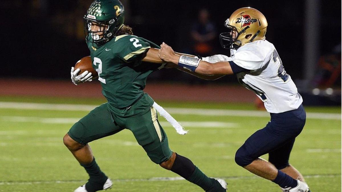 Saint Stephen’s running back Chase Brown (2) is grabbed by Bishop McLaughlin’s Bryant Beinhauer during Friday night’s game at Turner Field in Bradenton.
