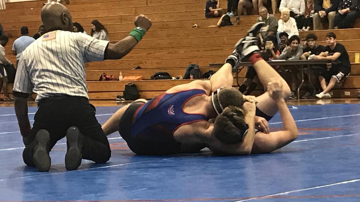 Manatee High wrestler Brandon Dossey, center, pinned North Port’s Evan Burch on Wednesday to help the Hurricanes win the sub-district dual meet title.